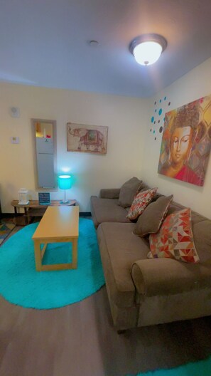 Ein Wohnzimmer mit einer Couch, einem Couchtisch, einer Lampe und einem Gemälde an der Wand.