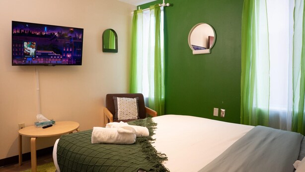 A hotel room with a bed, a TV, a chair, and a small table. - Downtown Apt Walk to all Stadiums Conv Center (Pittsburgh)