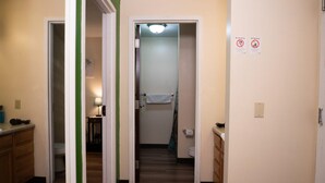 A hotel bathroom with a shower, toilet, and sink. There are signs indicating no smoking and no stealing. - Downtown Apt Walk to all Stadiums Conv Center (Pittsburgh)
