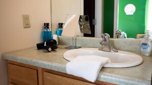 A bathroom with a sink, mirror, and countertop. There is a towel hanging on the counter, a bottle of soap, and a camera on the counter. - Downtown Apt Walk to all Stadiums Conv Center (Pittsburgh)