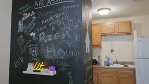 A kitchen with wooden cabinets, a white refrigerator, and a chalkboard wall with various messages and doodles. - 2 Bedroom 2 Bath City Views (Pittsburgh)