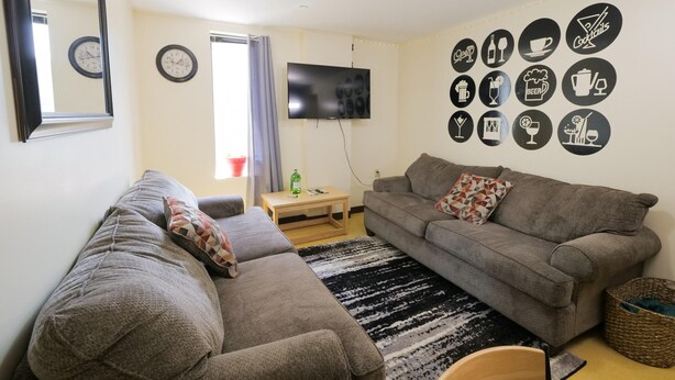 A living room with a grey sofa, a television, and a wall decorated with drink and food icons. - 2 Bedroom 2 Bath City Views (Pittsburgh)