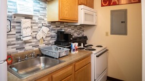 A kitchen with wooden cabinets, a white microwave, a stove, and a sink. There is a sign on the wall that reads "CAFE". - 2 Bedroom Downtown Apt Clean and Safe (Pittsburgh)