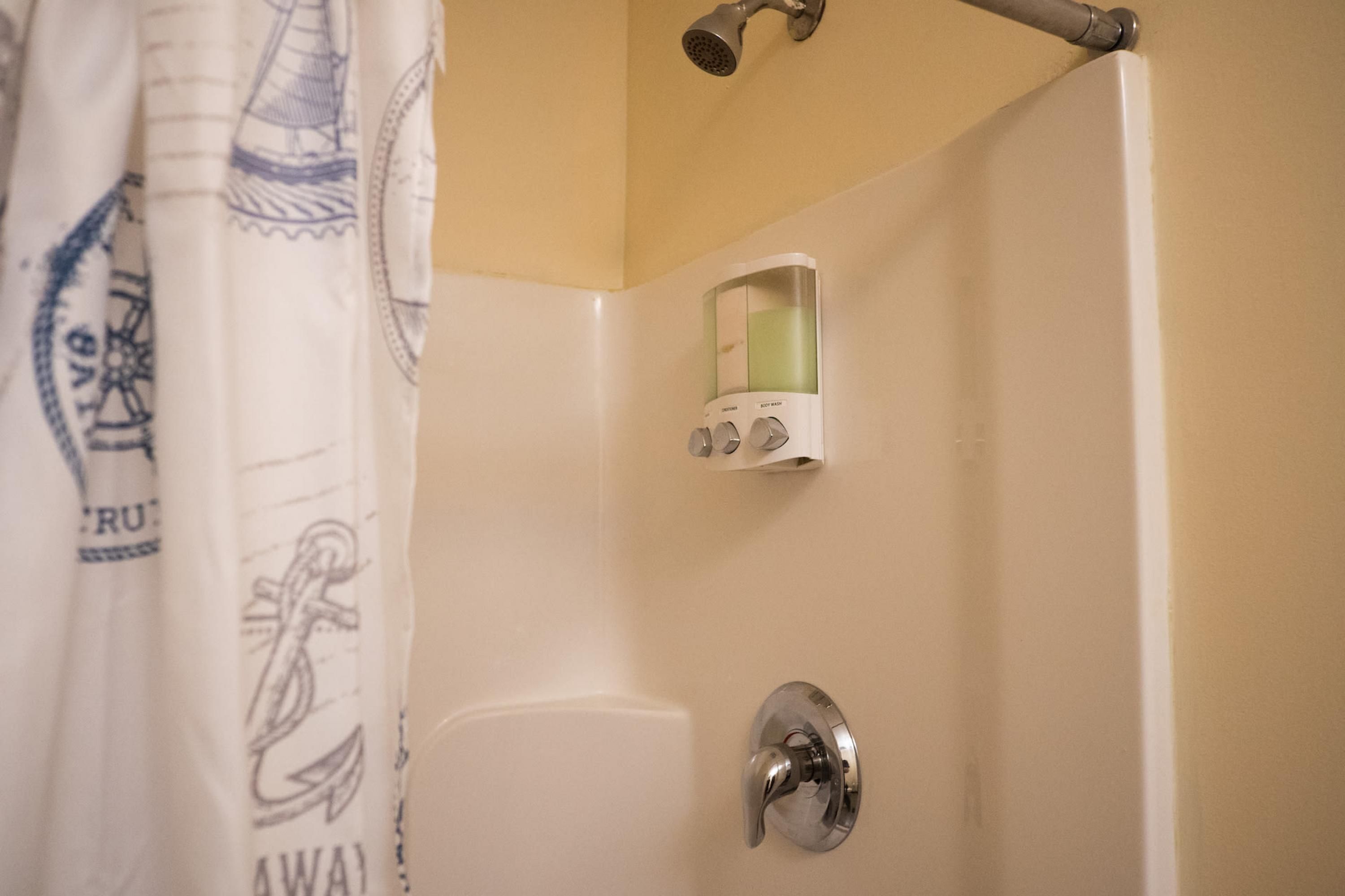 Un baño con ducha, toallero y dispensador de jabón.