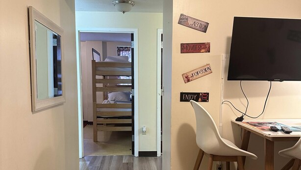 Ein Zimmer mit einem Etagenbett, einem Schreibtisch mit Stuhl, einem Fernseher und einer Wand mit Filmdekorationen.