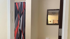 Ein kleines Badezimmer mit Toilette, Mülleimer und Duschvorhang.