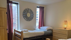 Ein Schlafzimmer mit einem Bett, einem Schminktisch, einem Spiegel und einem roten Teppich.