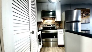 A compact kitchen with white cabinets, a stainless steel refrigerator, a built-in oven, and a microwave. - Stylish and Pet-Friendly Apartment in Beacon (Beacon)