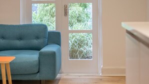 A room with a teal sofa, a small wooden table, and a white door with glass panels. - Stylish West End Detached Mews - Pass the Keys (Glasgow)