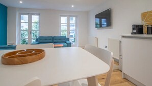 A modern kitchen with a dining area, a TV mounted on the wall, and a coffee machine on the counter. - Stylish West End Detached Mews - Pass the Keys (Glasgow)