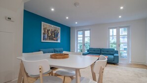 A modern living room with a white dining table, blue sofa, and a painting on the wall. - Stylish West End Detached Mews - Pass the Keys (Glasgow)
