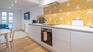 A modern kitchen with white cabinets, a built-in oven, and a large window. - Stylish West End Detached Mews - Pass the Keys (Glasgow)