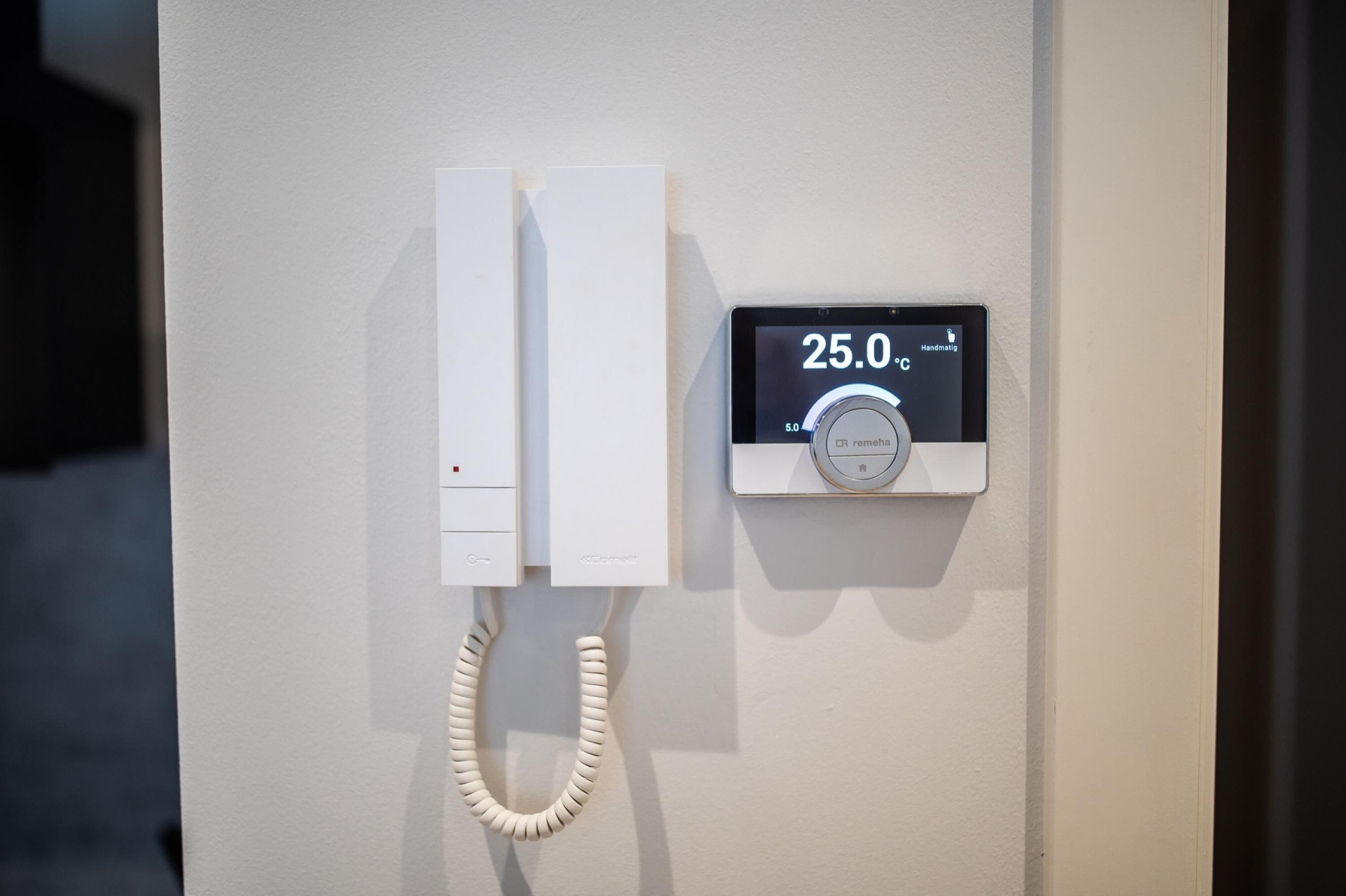 A thermostat displaying 25.0°C and a white telephone handset.