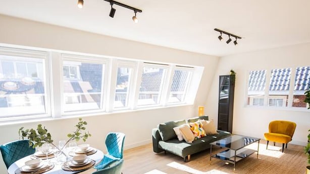 A bright living room with a dining area, large windows, and a sofa. - Serviced 1BR Apartments in Utrecht (De Bilt)