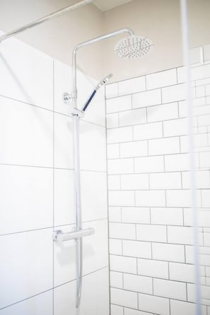 A shower with a handheld showerhead and a vertical rain showerhead.