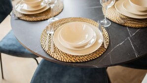 Una mesa con platos, tazones y vasos sobre individuales tejidos.