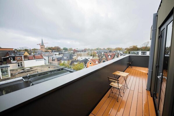 Una terraza en la azotea con cubierta de madera, una mesa y sillas.