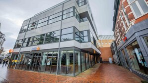 A modern building with a glass facade, a visible entrance, and a brick pathway. - Joyful Serviced Studio Apartment -ks71-j (Hilversum)