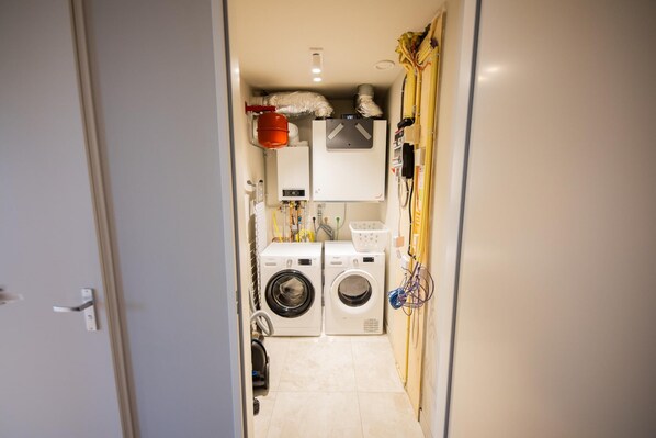 A laundry room with two washing machines, a dryer, and a water heater.