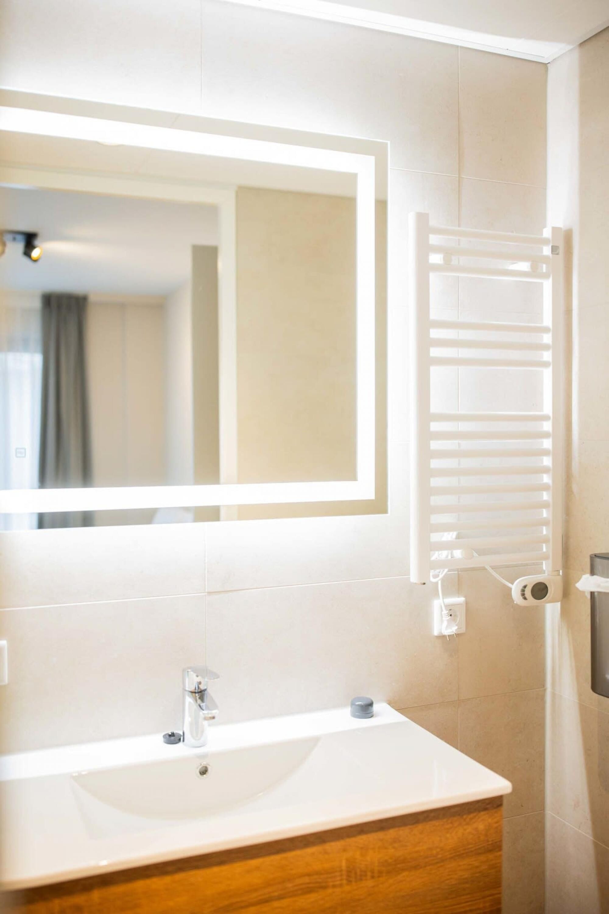 Een badkamer met een witte wastafel, een spiegel en een handdoekhouder.