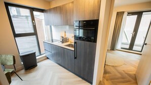 A modern kitchen with dark wood cabinets, a built-in oven, and a herringbone-patterned floor. - Alphabet Apartments 1BR Serviced Apartments (Hilversum)