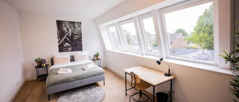 Un dormitorio con cama, escritorio, ventana y vistas al exterior.