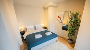 A modern bedroom with a bed, bedside lamps, a mirror, and a potted plant. - Studio Serviced Apartments With City View (Hilversum)