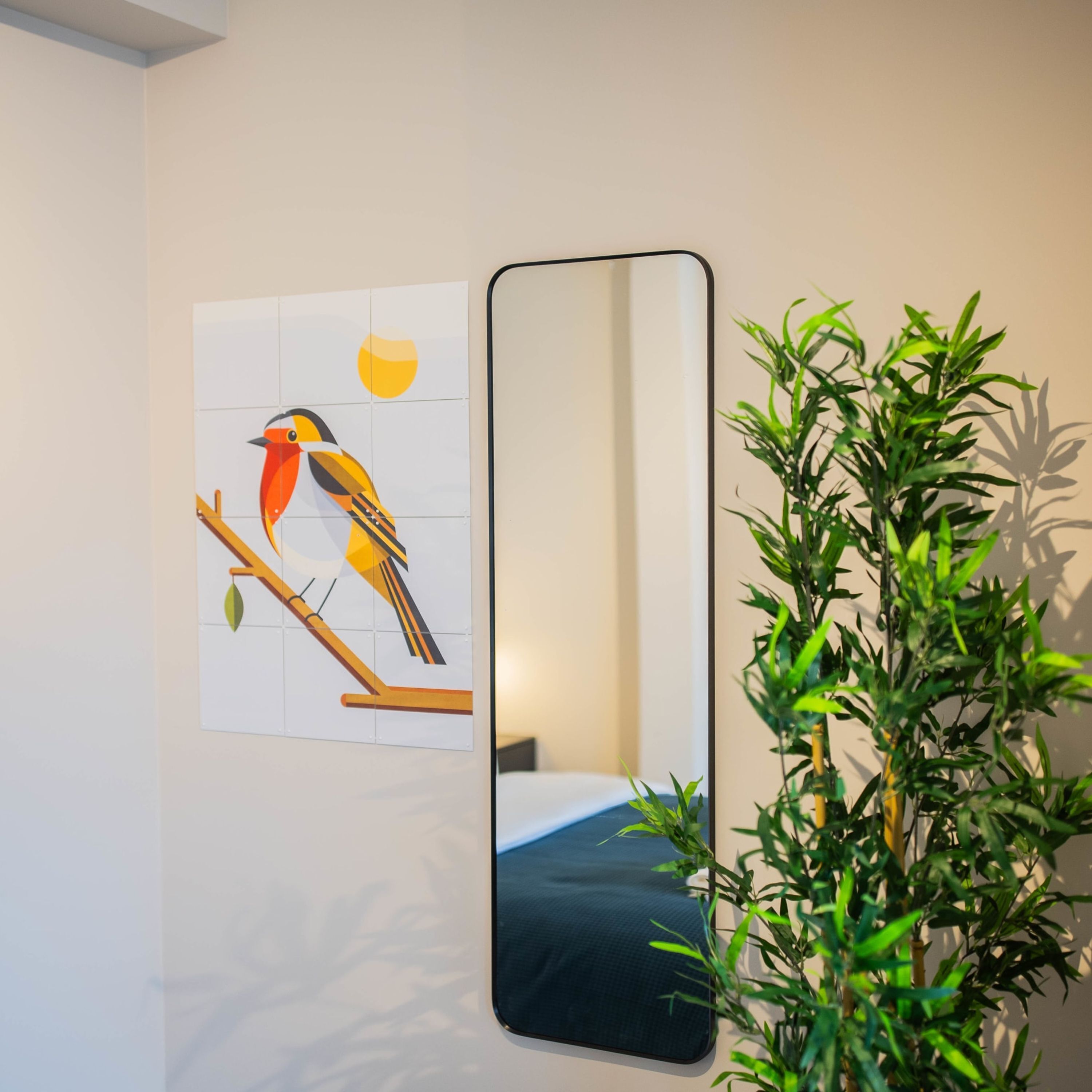 A room with a bed, a wall-mounted mirror, and a potted plant.