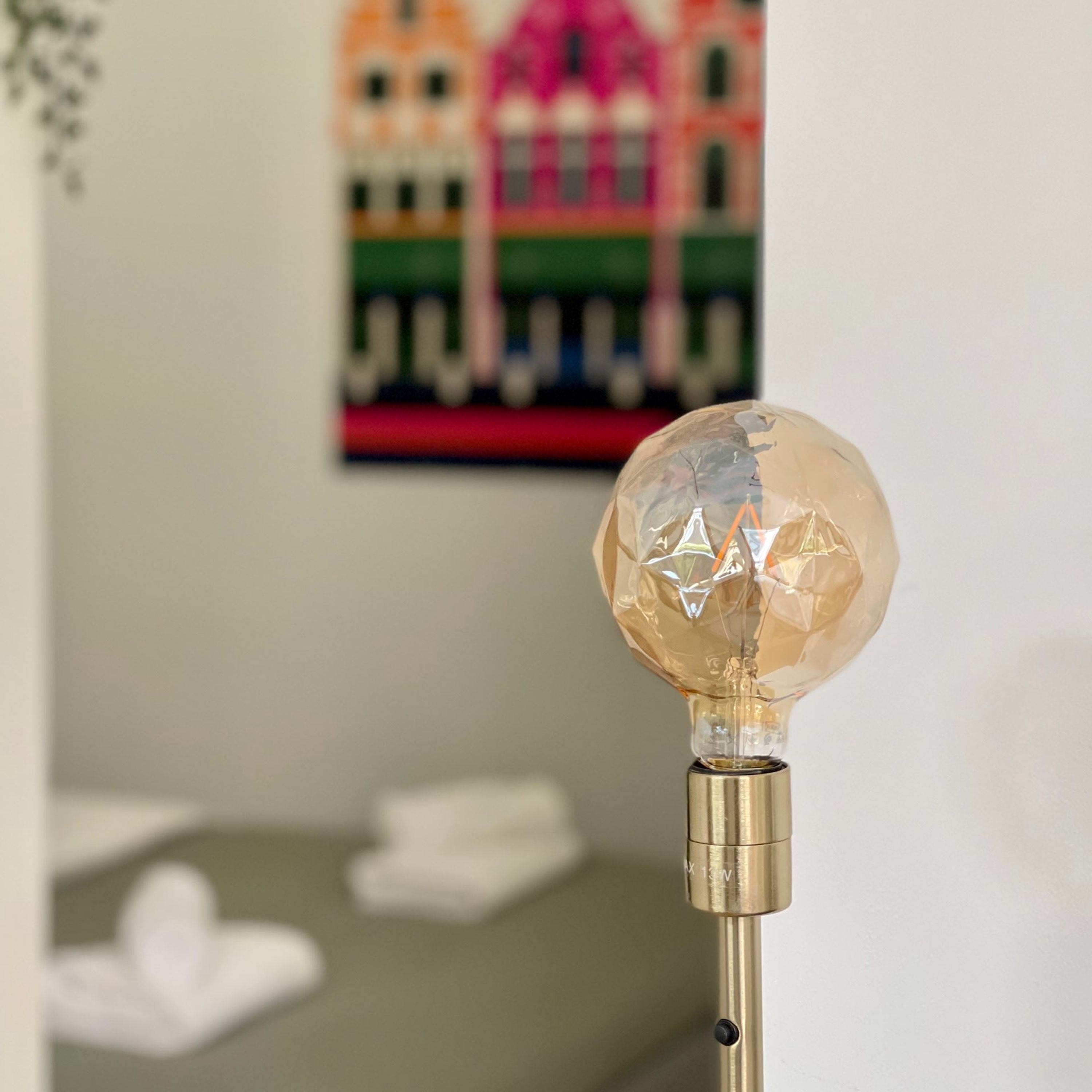 Een heldere glazen lamp op een metalen voet.