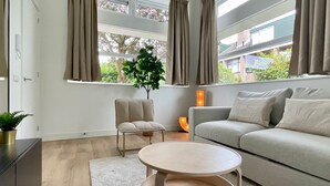 A modern living room with a sofa, a round coffee table, a chair, and a potted plant. - Serviced Studio Apartments in Utrecht (De Bilt)