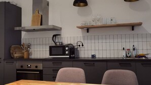 A modern kitchen with dark cabinets, a wooden dining table, and two pendant lights.