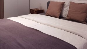 A bedroom with a bed, pillows, a nightstand, and a wardrobe.