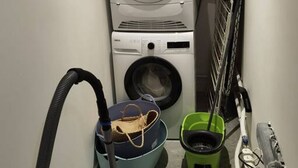 A laundry area with stacked washing machines and a vacuum cleaner.