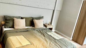 Ein modernes Schlafzimmer mit einem großen Bett, einem Nachttisch und Holzboden.