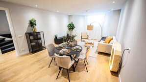 Een moderne woonkamer met een eethoek, met een ronde tafel met stoelen, een bank en een salontafel.