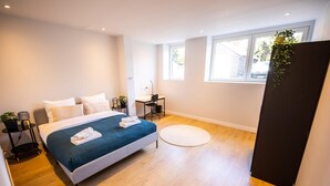 Een moderne slaapkamer met een bed, nachtkastjes, een bureau en een raam.