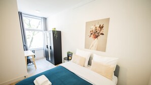 A modern hotel room with a large bed, a desk, and a chair. - Alphabet 1BR Serviced Apartment -nb304/306- (Rotterdam)