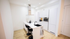 A modern kitchen with white cabinetry, a built-in oven, and a stainless steel range hood. - Alphabet 1BR Serviced Apartment -nb304/306- (Rotterdam)
