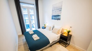 Een moderne slaapkamer met een bed, nachtkastje en uitzicht op het balkon.