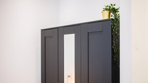 Een zwarte garderobe met een spiegel en een potplant erboven.