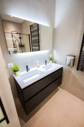 A modern bathroom with a double sink, a large mirror, and a towel rack.