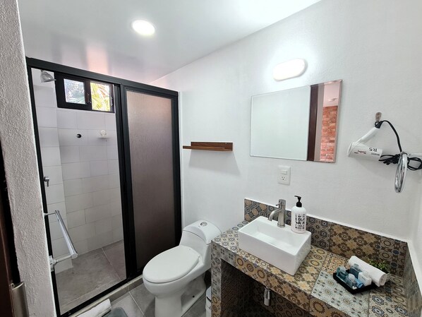 A bathroom with a toilet, sink, and shower.