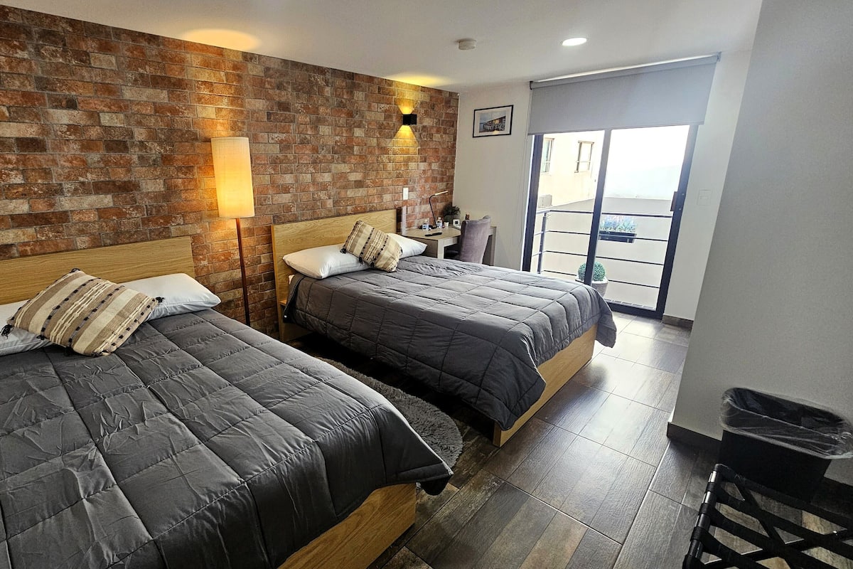 Une chambre avec deux lits, un mur en briques et un balcon avec vue.