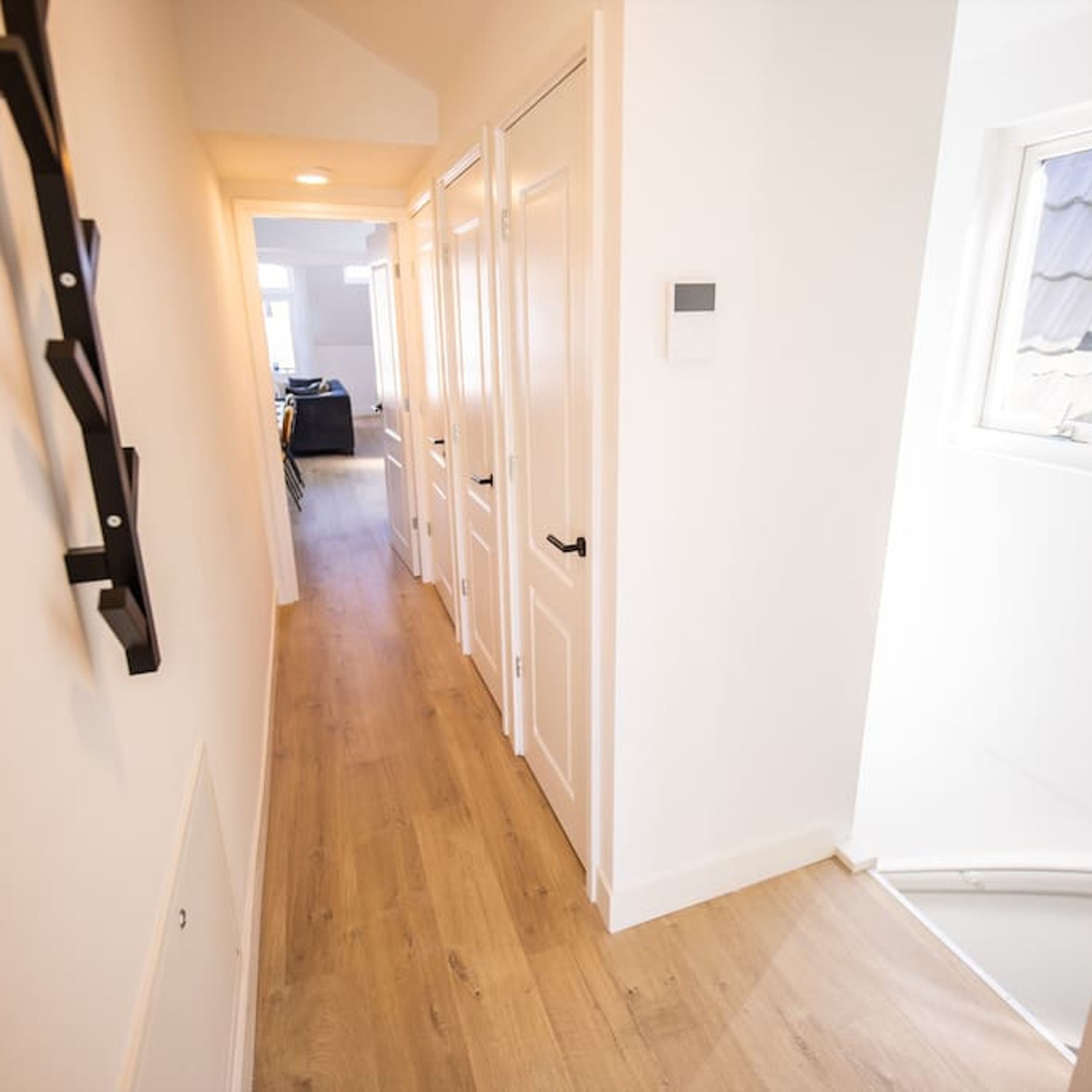 Un couloir avec un plancher en bois et des portes blanches.