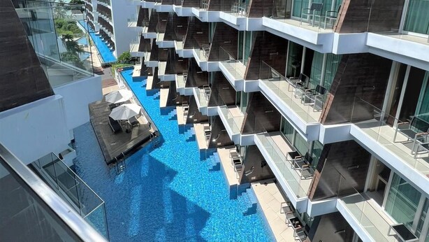 Ett modernt hotell med flera balkonger med utsikt över en central pool.