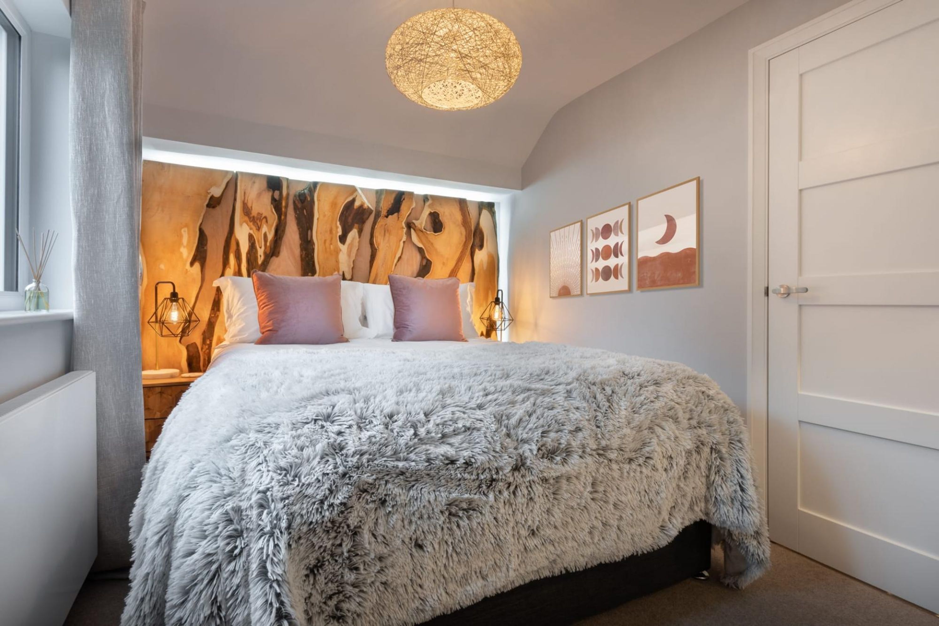 Un dormitorio con una cama grande, un tapiz de pared y obras de arte enmarcadas.
