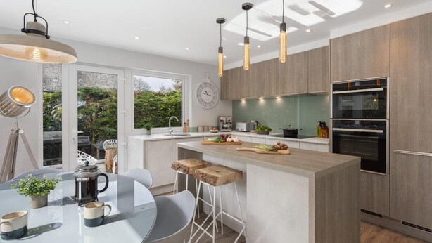 A modern kitchen with a central island, bar stools, a coffee table, and a view of the outdoors. - Woodlands Family Retreat - Windermere Lakedistrict (Windermere)