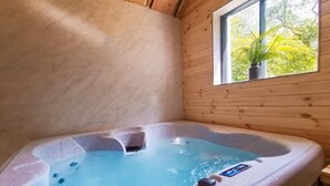 A hot tub in a wooden cabin with a window view of trees. - Woodlands Family Retreat - Windermere Lakedistrict (Windermere)