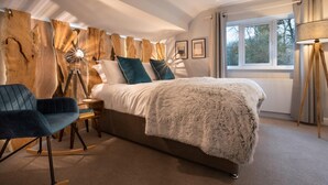 A bedroom with a large bed, a side table, a chair, a lamp, and a window with curtains. - Woodlands Family Retreat - Windermere Lakedistrict (Windermere)