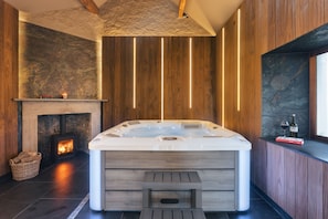 Un baño moderno con una bañera independiente, una pared de piedra, paneles de madera y una chimenea.